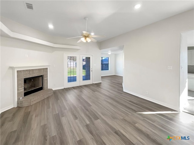 unfurnished living room with ceiling fan, a fireplace, and wood-type flooring