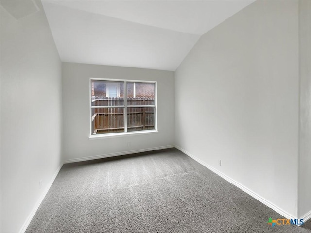 spare room featuring carpet and lofted ceiling