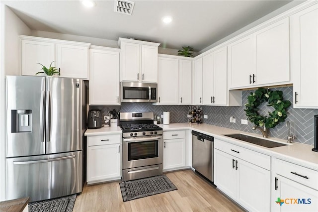 2024 Cowan Dr, New Braunfels, TX 78132 - kitchen featuring appliances with stainless steel finishes, white cabinets, light wood-style floors, and recessed lighting