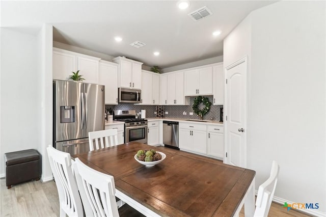 2024 Cowan Dr, New Braunfels, TX 78132 - kitchen with stainless steel appliances, backsplash, white cabinets, light wood finished floors, and light countertops