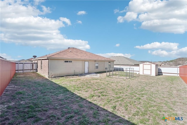 rear view of property featuring brick siding, a shed, a lawn, an outdoor structure, and a fenced backyard