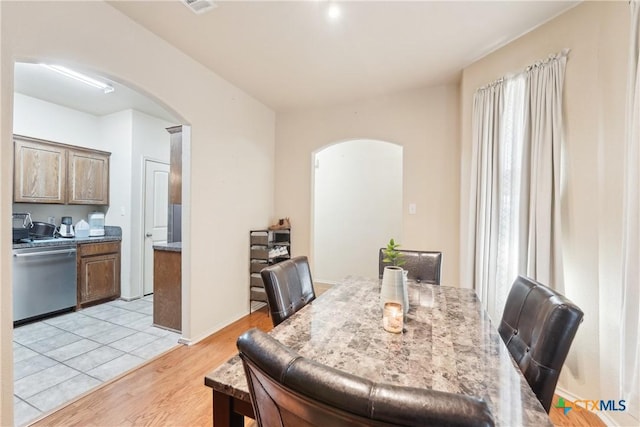 dining room with arched walkways and light wood finished floors