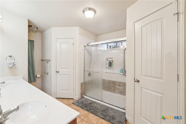 full bathroom with tile patterned flooring, a shower stall, double vanity, and a sink