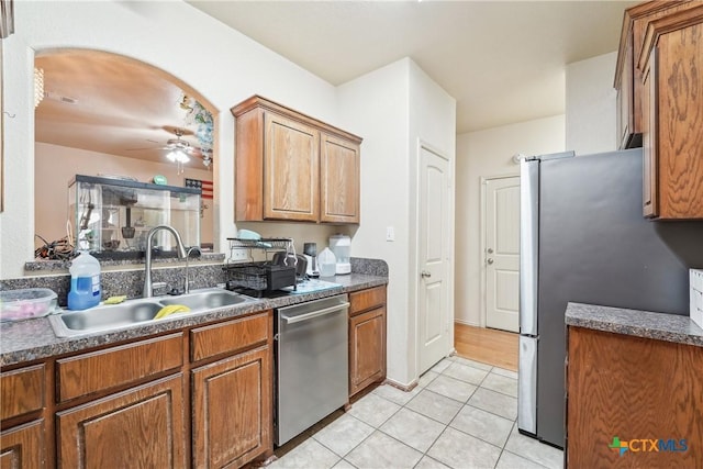 kitchen with a sink, arched walkways, dark countertops, and appliances with stainless steel finishes