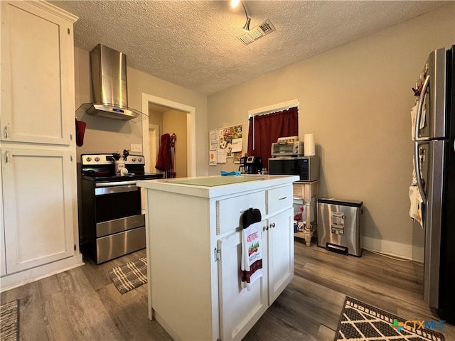 1308 E Park Ave, Victoria, TX 77901 - kitchen featuring wall chimney exhaust hood, appliances with stainless steel finishes, a kitchen island, dark wood finished floors, and white cabinetry