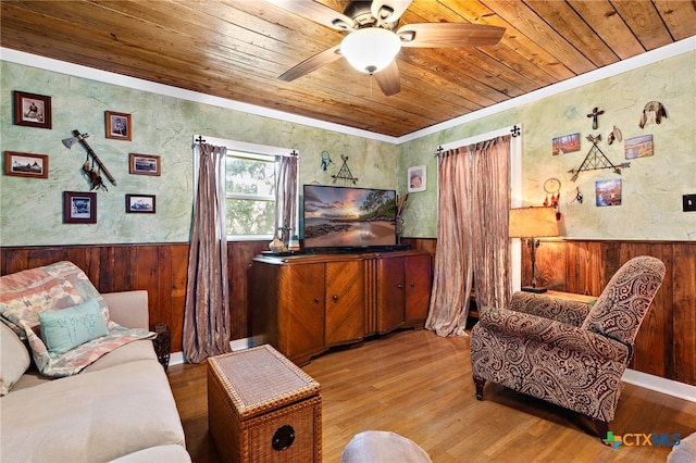 living room with wood ceiling, wooden walls, ceiling fan, crown molding, and light hardwood / wood-style flooring