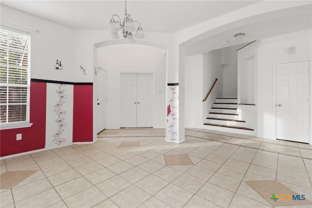 entryway with stairs, light tile patterned floors, arched walkways, and a notable chandelier