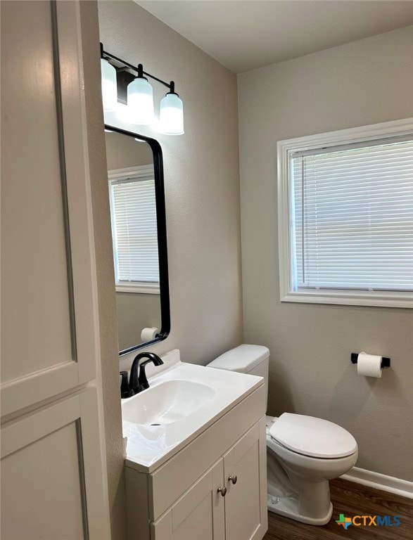 bathroom with hardwood / wood-style floors, vanity, toilet, and a healthy amount of sunlight