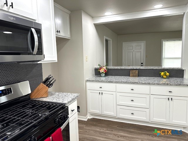 kitchen featuring stainless steel appliances, light stone countertops, decorative backsplash, white cabinets, and dark wood-type flooring