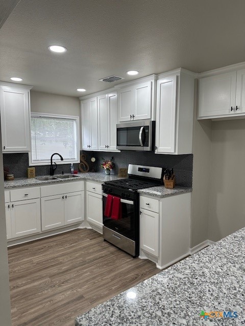 kitchen with stainless steel appliances, dark wood-type flooring, white cabinets, sink, and tasteful backsplash