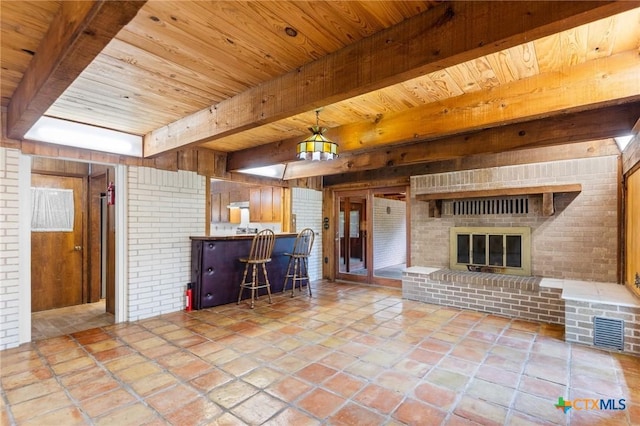 707 Dianne Dr, Copperas Cove, TX 76522 - living room with wooden ceiling with exposed beams, wood walls, a brick fireplace, and stone tile floors