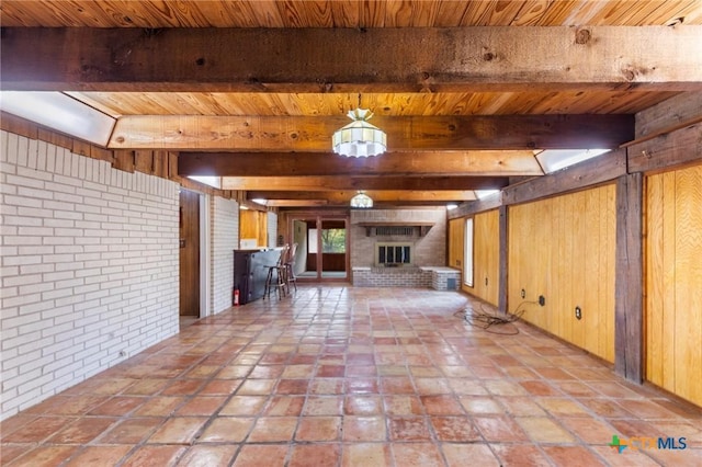 707 Dianne Dr, Copperas Cove, TX 76522 - unfurnished living room featuring wooden ceiling with exposed beams, brick wall, a brick fireplace, and wood walls