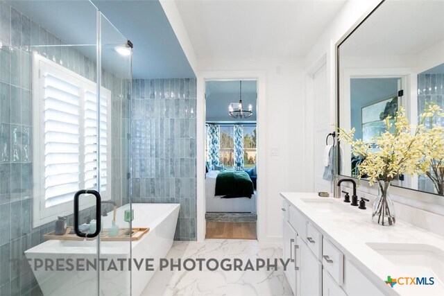bathroom with ensuite bathroom, marble finish floors, a freestanding tub, tile walls, and a chandelier