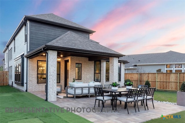 back of property featuring a patio, outdoor lounge area, brick siding, and a shingled roof
