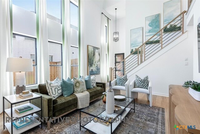 living room featuring healthy amount of natural light, a high ceiling, stairway, and wood finished floors