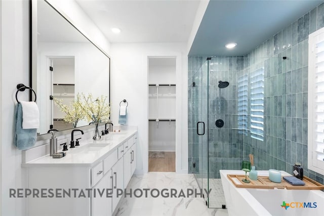 full bath featuring a stall shower, a spacious closet, a freestanding tub, double vanity, and marble finish floors