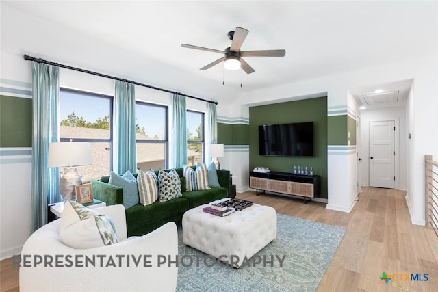 living room featuring a ceiling fan, attic access, wood finished floors, and baseboards