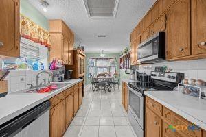 kitchen with decorative backsplash, a textured ceiling, stainless steel appliances, sink, and light tile patterned floors