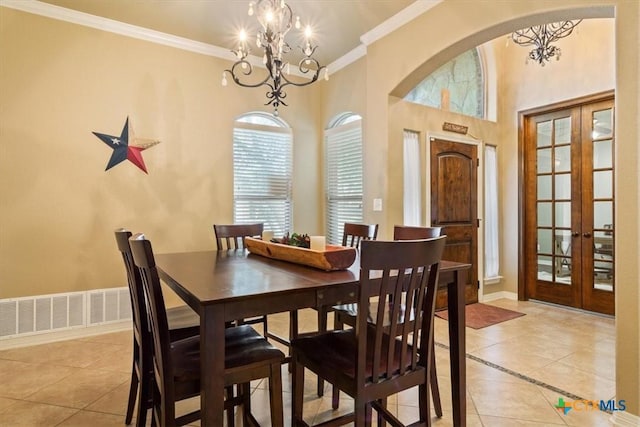 tiled dining area featuring a high ceiling, french doors, crown molding, and a notable chandelier