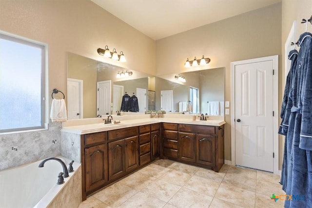 bathroom with vanity, tile patterned flooring, and tiled bath