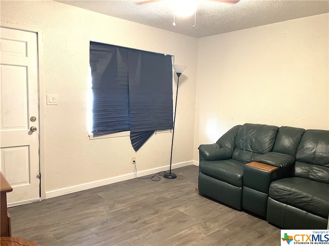 living room with a textured ceiling, dark hardwood / wood-style floors, and ceiling fan