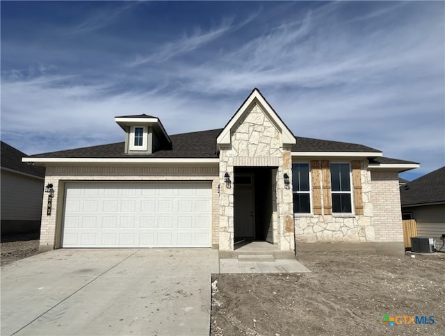 view of front facade with cooling unit, brick siding, driveway, and an attached garage