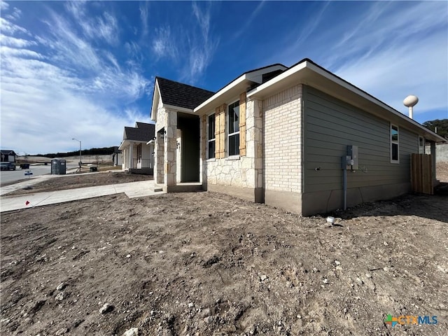 view of side of home with brick siding and a patio area