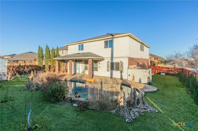 rear view of property featuring a patio area, brick siding, a lawn, and fence