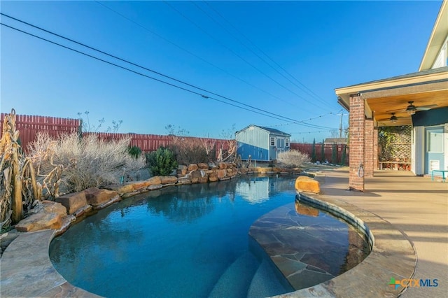 view of pool featuring a fenced backyard, an outdoor structure, a fenced in pool, a shed, and a patio area