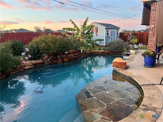 view of pool featuring a patio area, a fenced backyard, a fenced in pool, and an outbuilding