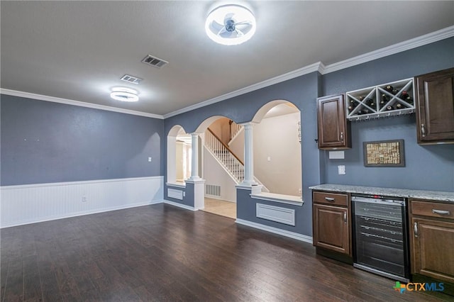 bar with visible vents, wine cooler, arched walkways, and dark wood finished floors