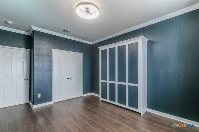 unfurnished bedroom with baseboards, crown molding, visible vents, and dark wood-type flooring