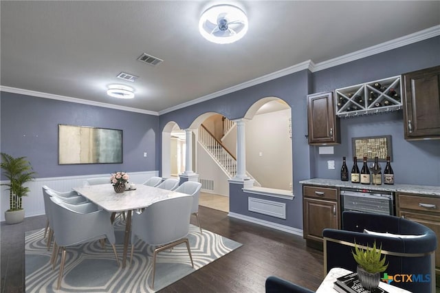 dining room featuring arched walkways, crown molding, and ornate columns