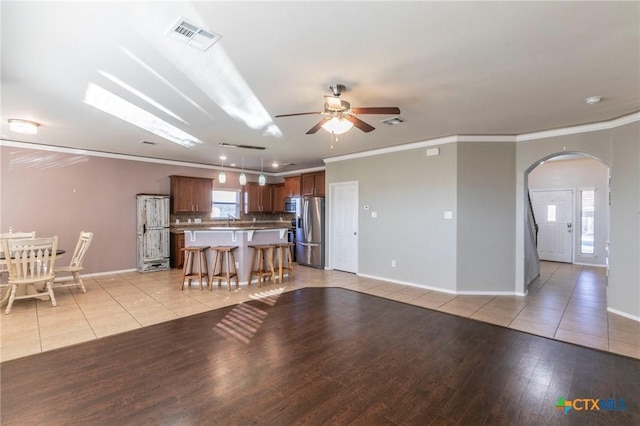 living room featuring light tile patterned floors, visible vents, arched walkways, and ornamental molding