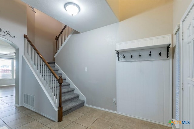 staircase featuring baseboards, visible vents, arched walkways, and tile patterned floors