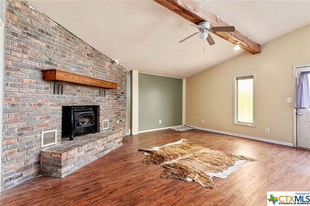 unfurnished living room with a wood stove, wood-type flooring, vaulted ceiling with beams, and ceiling fan