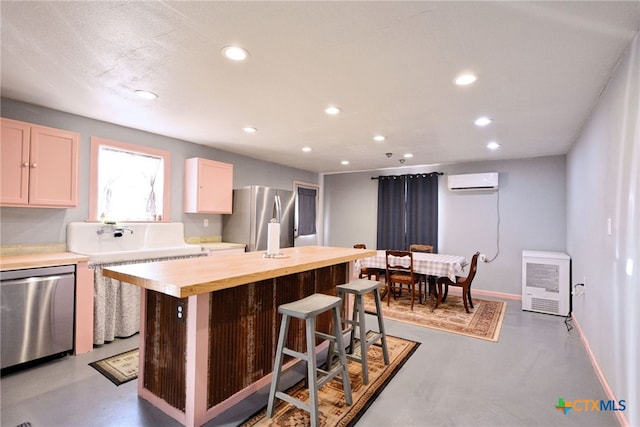 kitchen featuring butcher block countertops, stainless steel appliances, a center island, a kitchen breakfast bar, and a wall mounted air conditioner