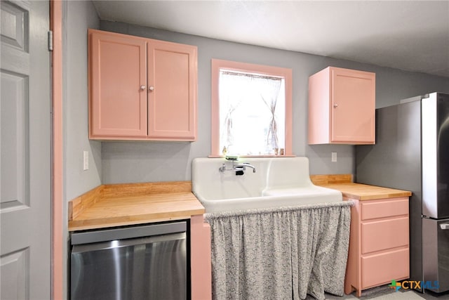 kitchen featuring appliances with stainless steel finishes, sink, light brown cabinetry, and butcher block countertops