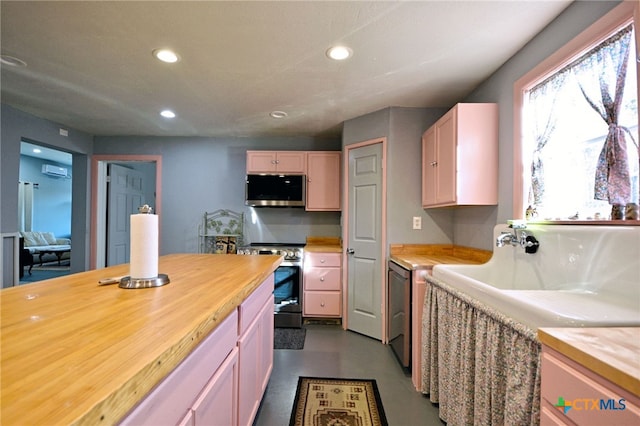 kitchen featuring light brown cabinetry, butcher block countertops, concrete floors, and appliances with stainless steel finishes