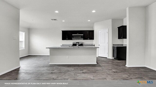 kitchen featuring a center island with sink, light stone countertops, dark wood-type flooring, and appliances with stainless steel finishes