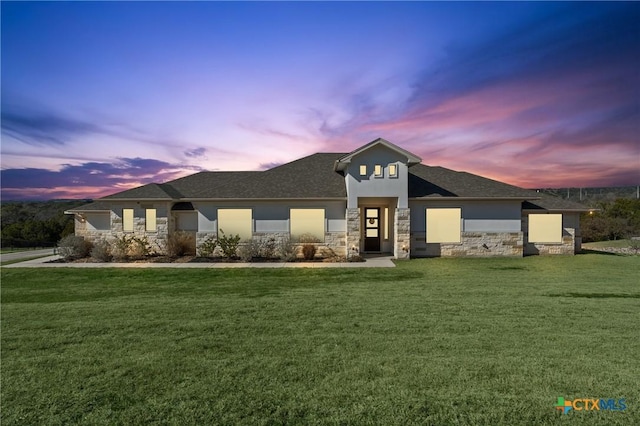 view of front facade featuring stone siding, a lawn, and stucco siding