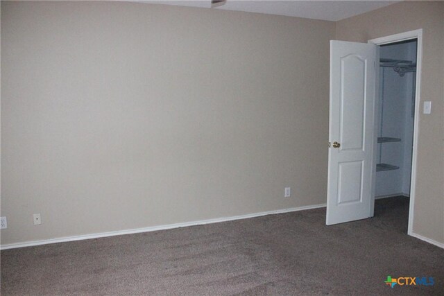 7710 Fallen Pne, Converse, TX 78109 - unfurnished bedroom featuring dark colored carpet, a walk in closet, and baseboards