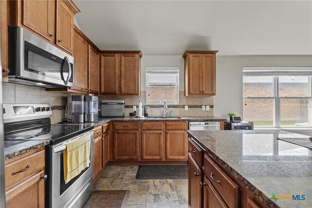 6203 Morganite Dr, Killeen, TX 76542 - kitchen featuring appliances with stainless steel finishes, backsplash, dark stone countertops, and brown cabinetry