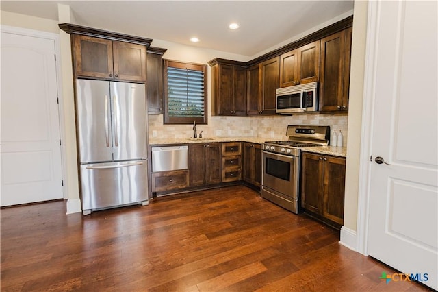 kitchen with stainless steel appliances, dark wood-type flooring, dark brown cabinetry, and light stone counters