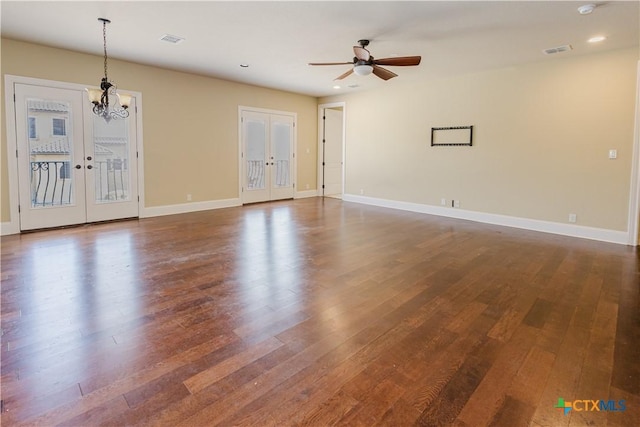 unfurnished room featuring french doors, ceiling fan with notable chandelier, and dark wood-type flooring