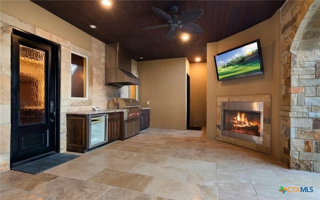 kitchen featuring exterior fireplace, dark brown cabinets, wood ceiling, and wall chimney exhaust hood