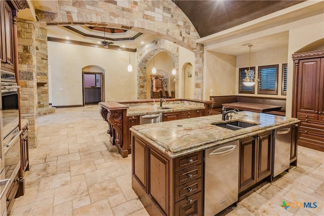 kitchen featuring decorative light fixtures, sink, oven, ceiling fan, and a spacious island