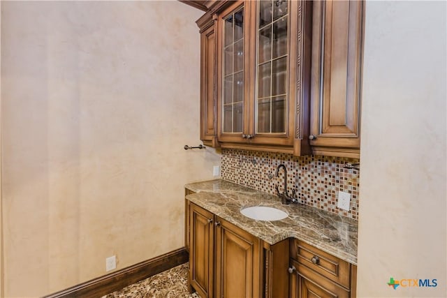 bar with tasteful backsplash, sink, and stone countertops