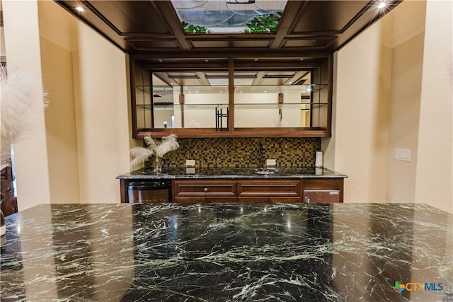 kitchen featuring decorative backsplash, dark stone counters, and dishwasher