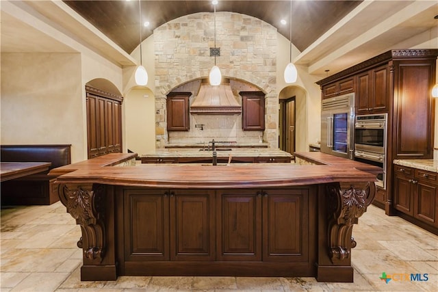 kitchen with lofted ceiling, stainless steel appliances, a large island, and butcher block countertops